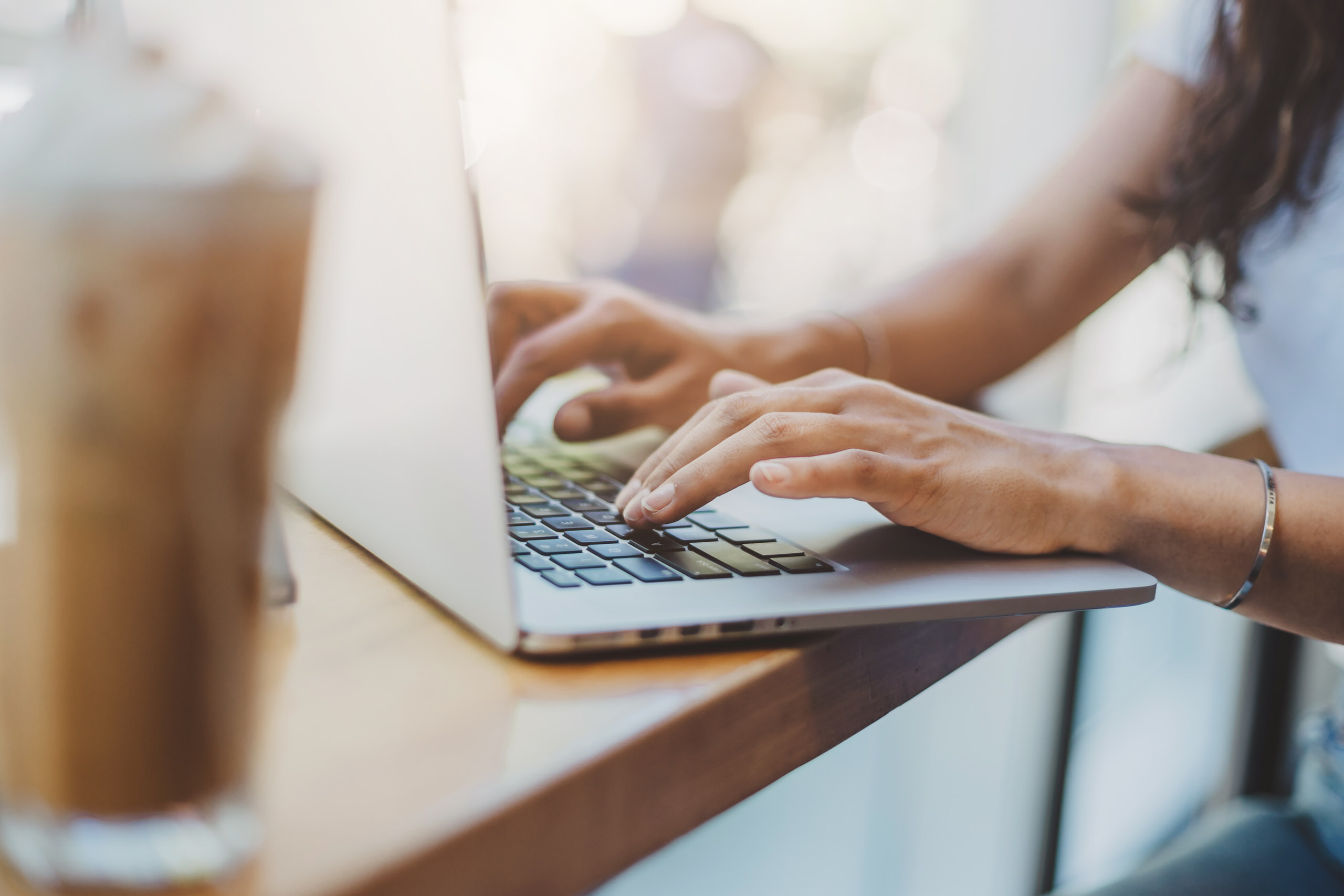 Cropped image of woman's hands typing on laptop